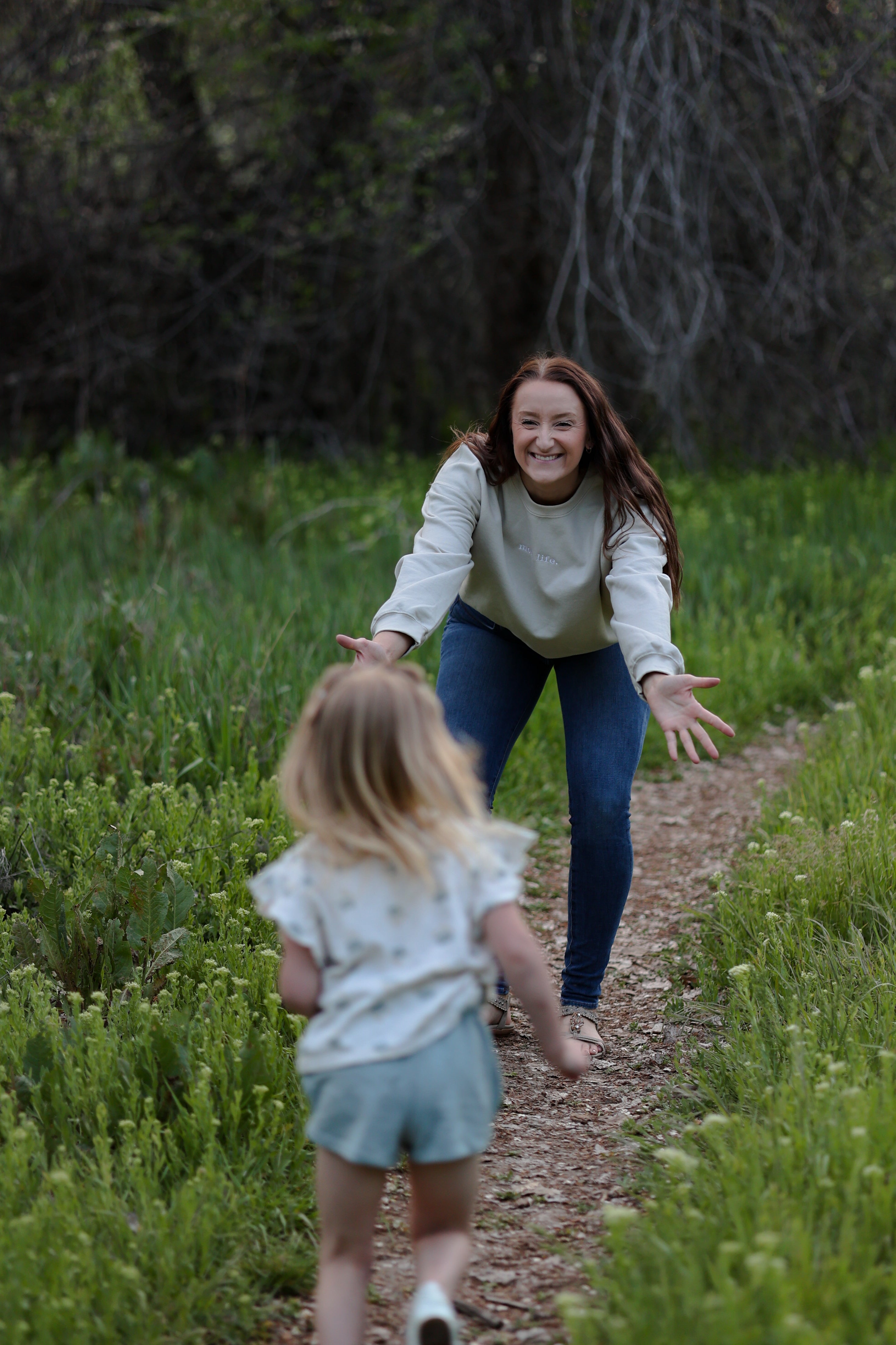 Woman and child walking on a path through a grassy field in rooted (sand)