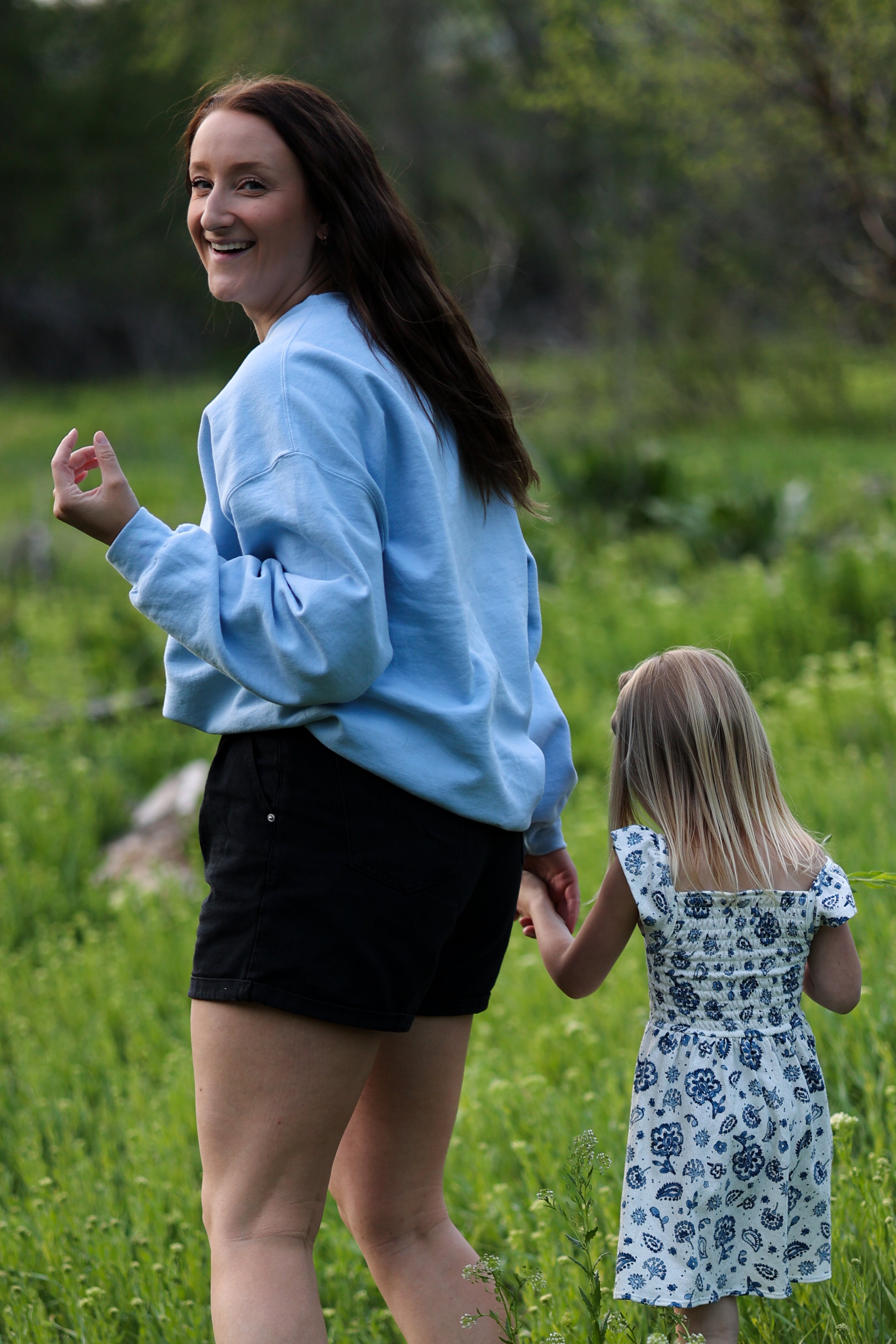 mother and daughter walking together in a green field in steady (light blue)