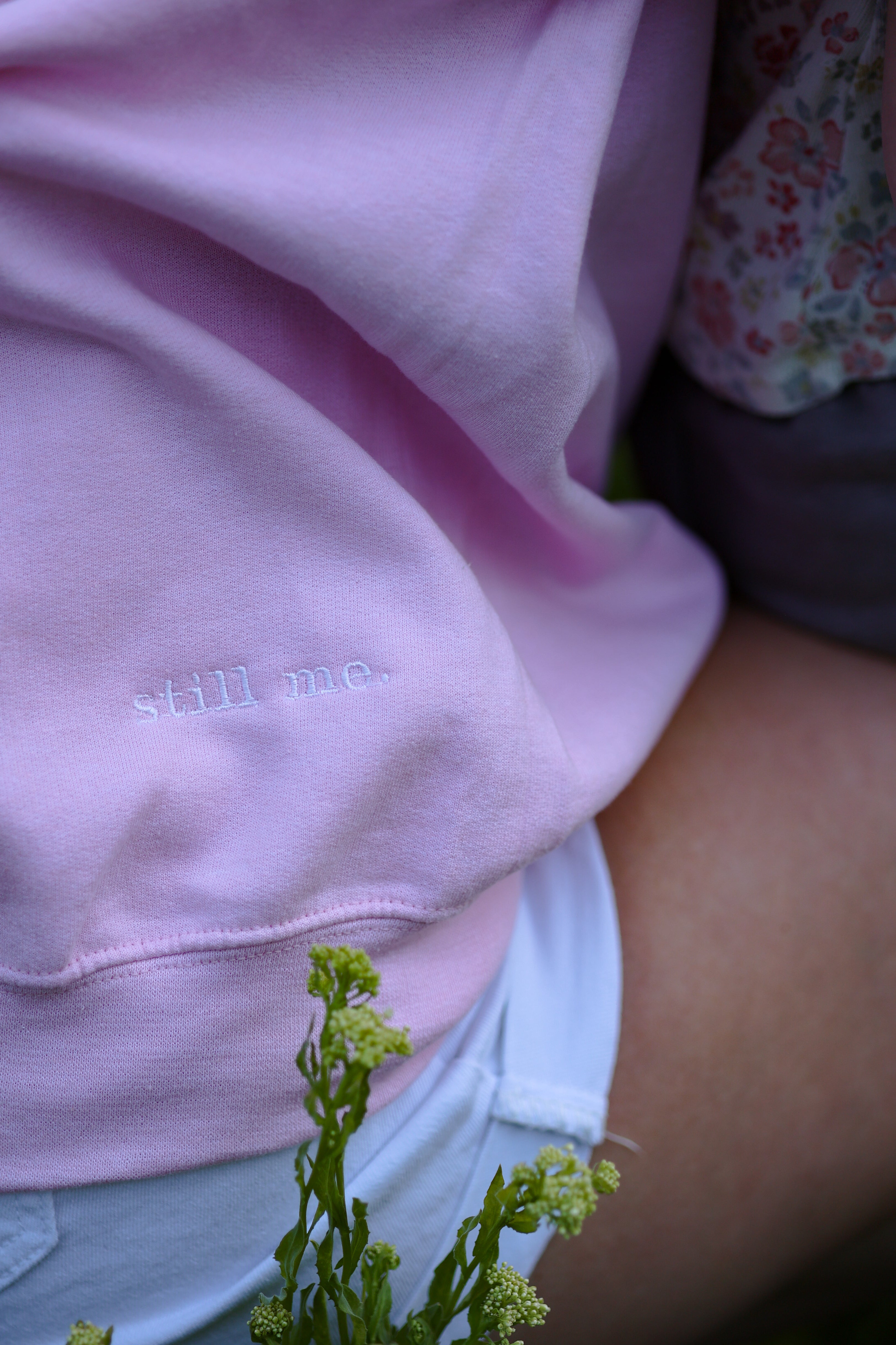 light pink sweatshirt with 'still me' text, worn by a person sitting outdoors. in tender (light pink)